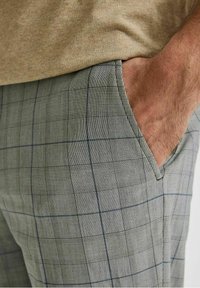 Pánské kalhoty ze šedé látky s jemným kostkovaným vzorem, s námořnickými akcenty, rovného střihu a bočními kapsami.