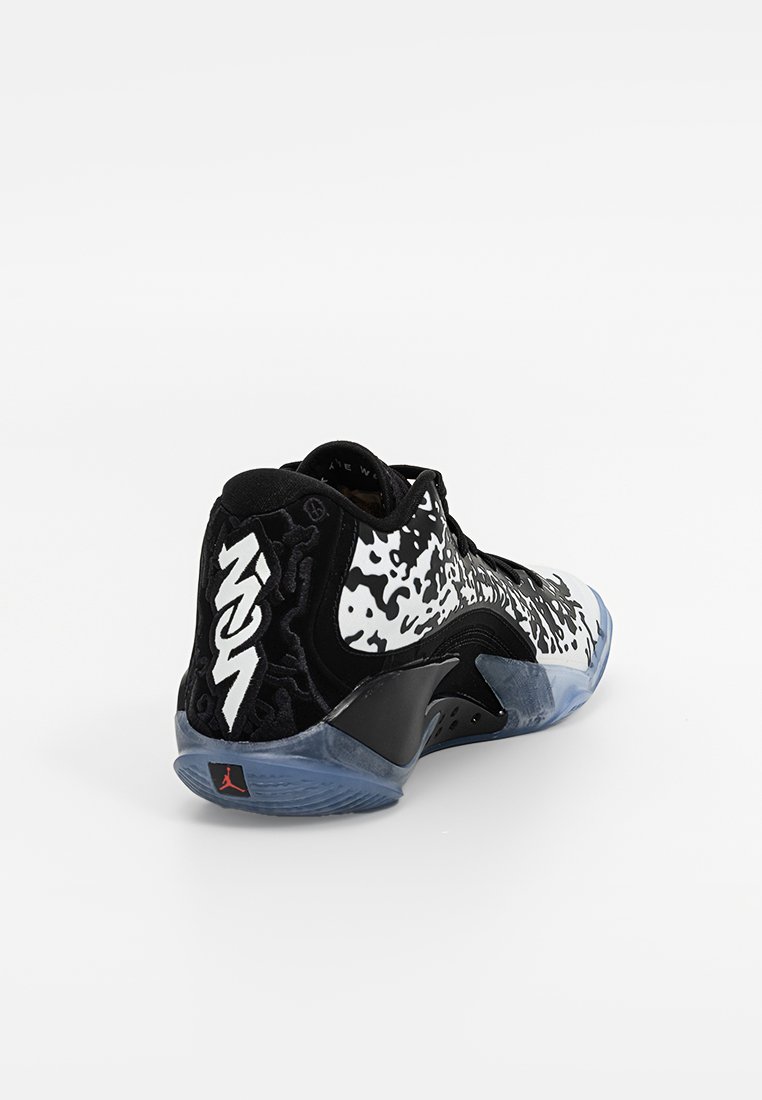 Baskets noires et blanches avec un dessus à motifs, des accents en daim et une semelle bleue translucide affichant un logo sur le talon.