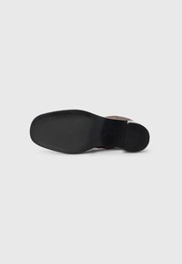 Brązowa zamszowa podeszwa buta, z gładką czarną gumową podeszwą zewnętrzną, zaokrąglonym noskiem i minimalnym bieżnikiem. Czysty design bez widocznych wzorów.