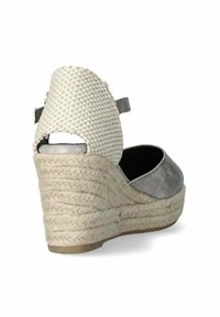 Scarpa con zeppa con tomaia in tessuto intrecciato beige, accentuata in suede grigio, e tacco avvolto in juta. Presenta un retro aperto e una cinghia alla caviglia.
