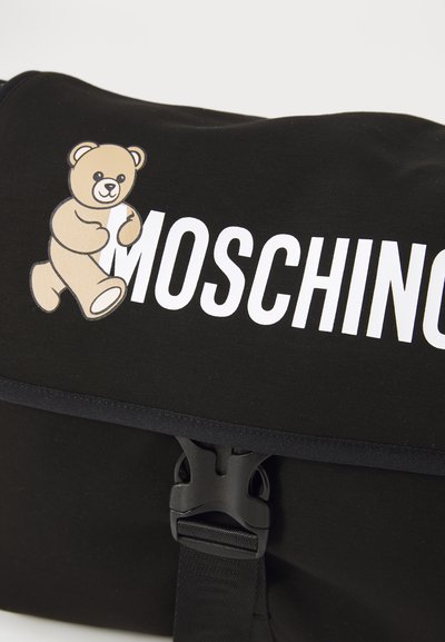 Svart tygväska med vit text "MOSCHINO" och en beige teddy-björnsgrafik på locket, säkrad med en svart plastspänne.