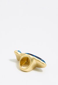 Gouden ring met een brede, gladde band en een grote ovale steen met blauwe en zwarte accenten. Gecontroleerde randen benadrukken het ontwerp.