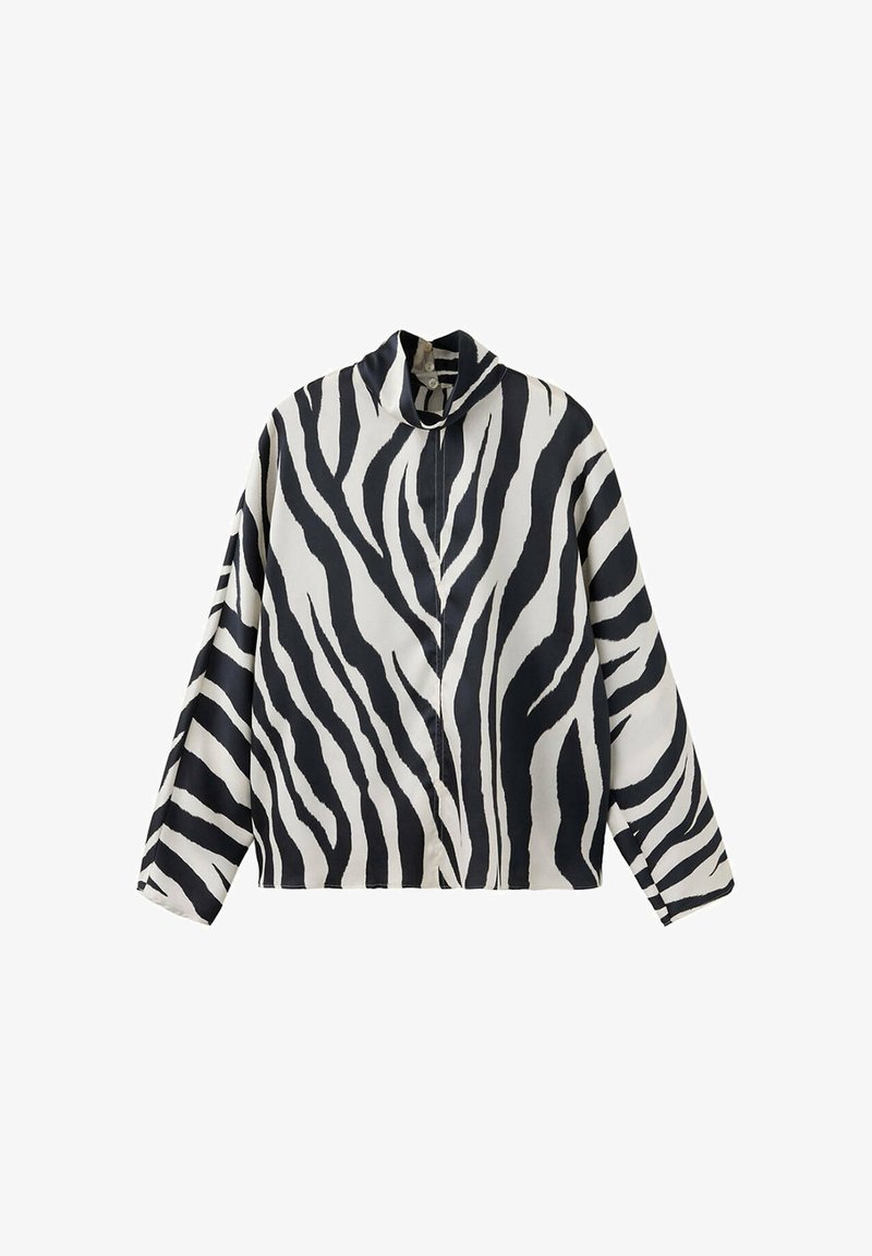 Chemise à manches longues boutonnée avec un imprimé zèbre noir et blanc et un col plié, présentée sur un fond blanc uni.