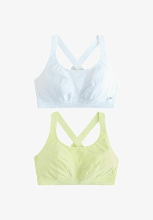 Two seamless sports bras with crossed straps, one white and one pale yellow, displayed flat on a white background.
