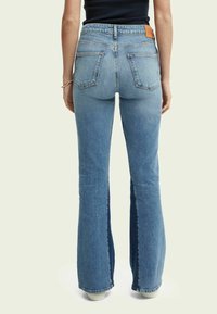 Blå denim flare-jeans med medelhög midja, utrustade med två bakfickor och en ljus tvätt. Sidsömmarna har en insats av mörkare denim.