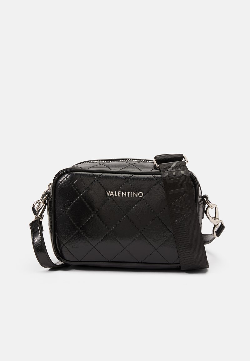 Černá prošívaná kožená crossbody taška se stříbrným kováním a odnímatelným popruhem, s uzavíráním na zip a reliéfním logem na přední straně.