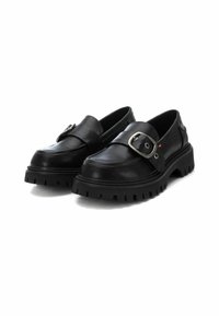 Mocasines de cuero negro con una correa ancha y hebilla metálica, que cuentan con una suela de goma gruesa y texturizada con surcos profundos para un mejor agarre.