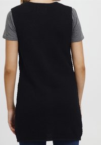 Czarny dzianinowy top bez rękawów o teksturowanej powierzchni. Połączony z szarą koszulką z krótkim rękawem, z okrągłym dekoltem i luźnym krojem.