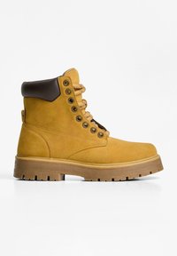 Gelbe Leder-Ankle-Boots mit braunen Akzenten, Metallösen und gemusterten Schnürsenkeln. Verfügt über eine robuste, strukturierte Gummisohle.