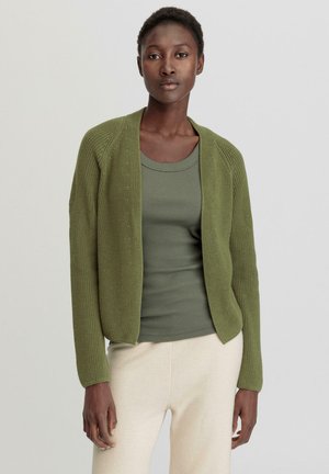 Olijfgroen cardigan met een gemêleerd breipatroon, open voorkant en lange mouwen, gecombineerd met een bijpassende groene tanktop en lichtbeige broek.