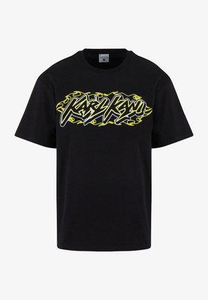 Camiseta de algodón negra con letras blancas en negrita "Karly Kani" rodeadas de llamas amarillas. Cuello redondo, corte relajado, mangas cortas.