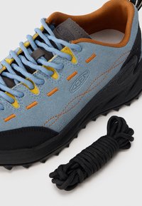 Γαλάζιο σουέντ παπούτσι με πορτοκαλί και κίτρινες λεπτομέρειες, μαύρη λαστιχένια σόλα και υφή. Περιλαμβάνει ξεχωριστό μαύρο κορδόνι.