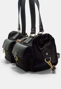 Sac en daim noir avec deux poches avant, quincaillerie dorée, double anses et une forme structurée. Comprend un fermoir et des détails décoratifs.