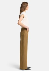 Pantaloni khaki a vita alta, morbidamente aderenti, realizzati in cotone, dotati di tasche laterali e design a gamba dritta.