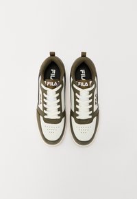 White and olive green athletic shoes with lace closure, perforated toe, and Fila logo on the tongue. Textured fabric with rubber sole.