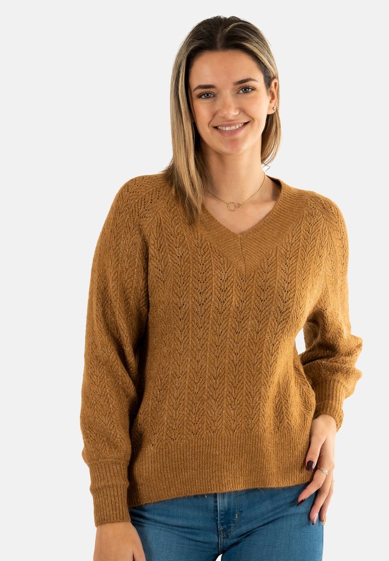 Suéter de cuello en V y mangas largas en un cálido color marrón con un patrón de espiga texturizado, puños y cinturilla acanalados, combinado con jeans azules.