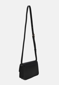 Borsa a spalla nera con chiusura a linguetta, realizzata in materiale liscio. Presenta una tracolla regolabile e dettagli in metallo color oro.