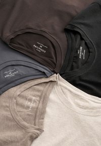 Fünf Baumwoll-T-Shirts in Dunkelbraun, Grau, Schwarz, Beige und Hellcreme. Jedes hat einen Rundhalsausschnitt und trägt innen "NEXT SIGNATURE"-Etiketten.