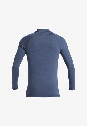 Dlhý rukáv, priliehavá športová košeľa z texturovanej tmavomodrej látky. Obsahuje vysoký golier a ploché švy pre pohodlie.