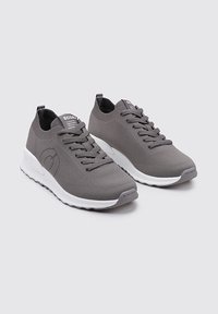 Zapatillas de punto grises con una superficie texturizada, que cuentan con una suela blanca, cordones y un acento de logo en el lateral. Diseño flexible para mayor comodidad.