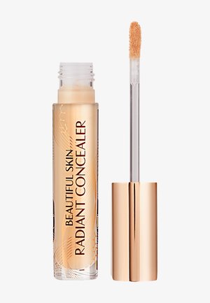 Tube transparent de correcteur éclatant avec un capuchon doré, doté d'un applicateur en feutre. Le texte sur le tube indique "CORRECTEUR ÉCLATANT PEAU MAGNIFIQUE".