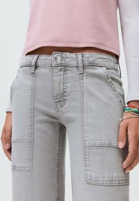 Jeans cargo grigi con borchie argentate lungo la vita e le tasche, caratterizzati da una vestibilità dritta e tasche applicate sui lati.