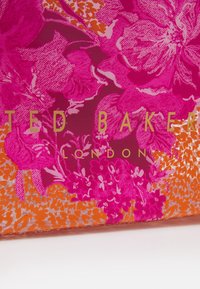 Conception florale rose avec des accents orange et des lettres dorées. Le matériau semble lisse et brillant, présentant différents motifs de fleurs.