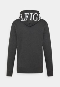 Felpa con cappuccio grigio scuro, con maniche lunghe e grande testo bianco che spellaccia parzialmente "TOMMY HILFIGER" sulla parte posteriore del cappuccio.