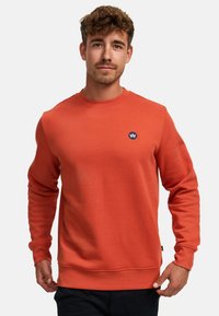 Sudadera de algodón naranja con mangas largas, puños acanalados y cuello redondo. Presenta un pequeño logo azul oscuro en el pecho.