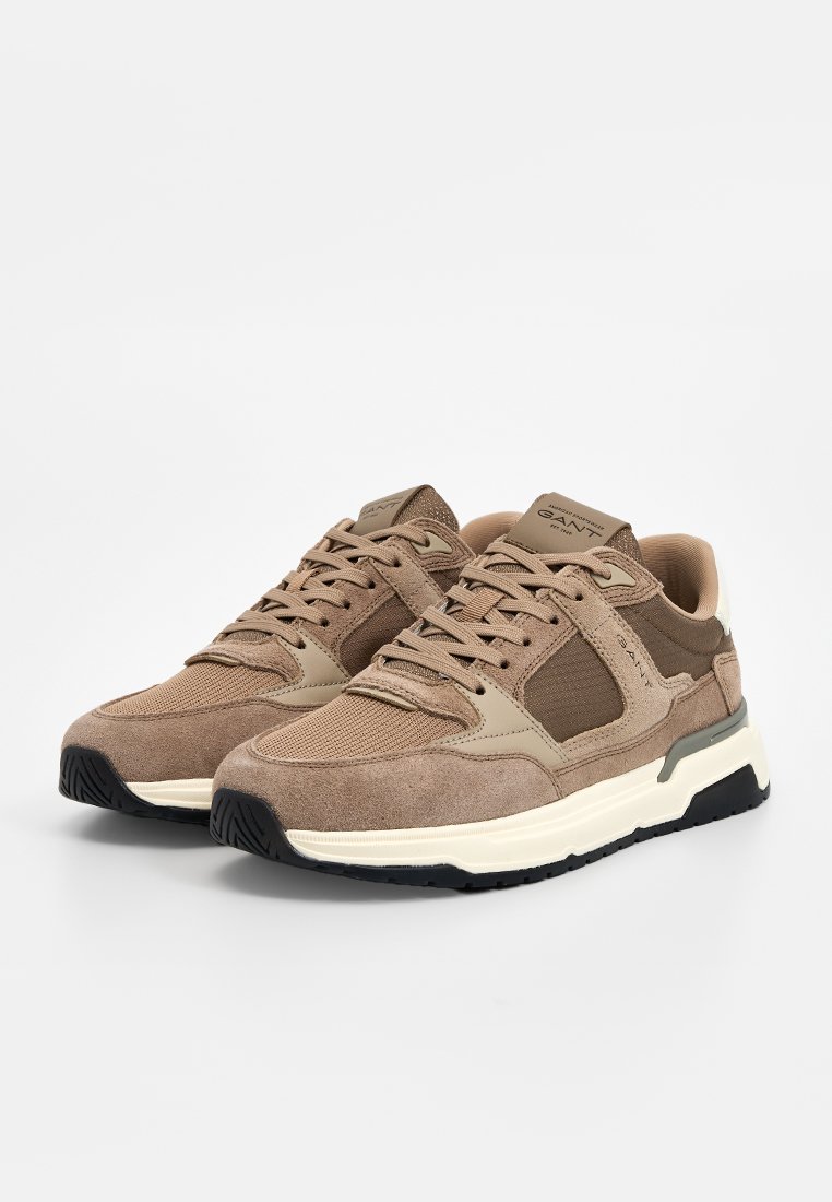 Baskets de sport marron en suède et mesh, avec un bout arrondi et des accents contrastants beiges et noirs sur la semelle.