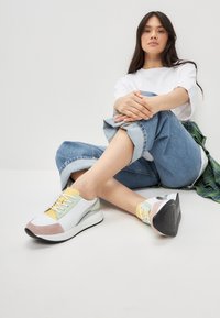 Zapatillas que combinan materiales en blanco, amarillo, verde menta y rosa claro. Diseño de perfil bajo con punta redonda y suela texturizada.