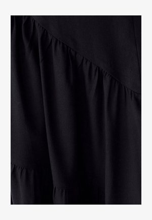 Schwarzes Kleid mit geschichteten Rüschen, strukturiertem Stoff und einem diagonalen Nahtdesign. Glatte Oberfläche mit kontrastierendem, gerafftem Detail am Saum.