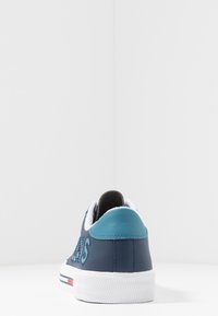 Navy leather sneaker with turquoise accents, white sole, and textured grip. Features stitched branding on the side and padded collar.