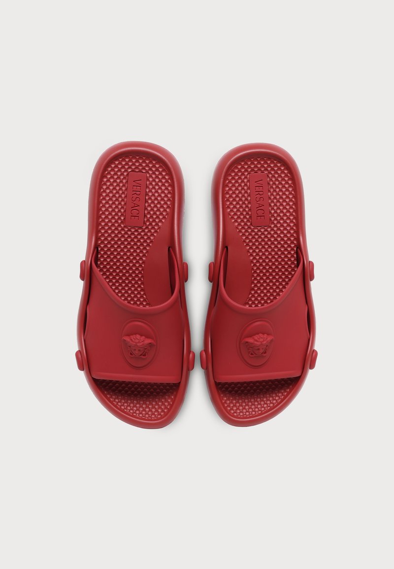Paar rote Versace Gummi-Slide-Sandalen mit strukturierten Fußbetten und Medusa-Kopf-Logos auf den Riemen, von oben auf weißem Hintergrund gezeigt.