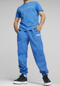 Blå bomulls t-shirt och matchande joggers med kontrasterande vita grafiska linjer och logotyper. Kombinera med svarta sneakers för en avslappnad look.