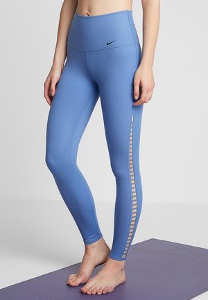 Niebieskie legginsy high-waisted o gładkiej fakturze, z bocznym panelem z siateczki z wycięciem. Logo Nike nad paskiem.