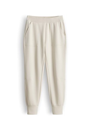 Crèmekleurige joggingsbroek met elastische tailleband, zijzakken en geribbelde boorden op een witte achtergrond.