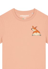 Perzikkleurig t-shirt van zacht stof met een cartoon corgi ontwerp op de linkerkant van de borst. Ronde halslijn en korte mouwen.