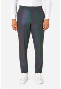 Donkere, glanzende broek met iriserende afwerking, ontworpen met een rechte snit, ritssluiting en knoopsluiting. Draagt een wit overhemd en sneakers.