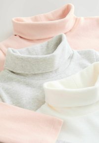 Trzy golfy w odcieniach różowym, jasnoszarym i kremowym, wykonane z miękkiego materiału, z podwiniętym kołnierzem oraz ściągaczami na rękawach.