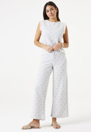 Ensemble en tissu texturé bleu clair et blanc, comprenant un débardeur à bords volants et un pantalon à jambes larges. Portez-le avec des sandales neutres.