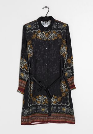 Černé dlouhé šaty s květinovými vzory v bílé a oranžové barvě. Mají límec, zapínání na knoflíky vpředu a pás na zavazování v pase. Texturovaná látka s dekorativním lemem.