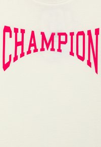 Sudadera color crema con grandes y audaces letras fucsias que escriben "CAMPEÓN" en un diseño arqueado a lo largo del pecho. Textura suave.