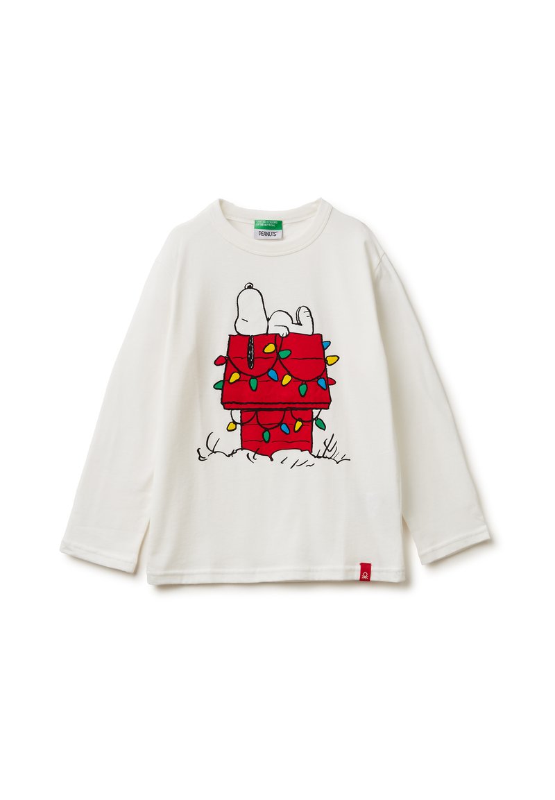 Biała koszula z długim rękawem z grafiką Snoopiego na czerwonym domku dla psa ozdobionym kolorowymi światełkami bożonarodzeniowymi. Czerwona metka przy dolnym brzegu.