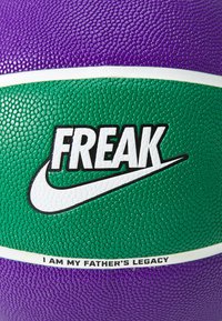Un ballon de basket Nike avec une surface texturée en violet et vert. Du texte notable comprend "FREAK" et "JE SUIS L'HÉRITAGE DE MON PÈRE" en blanc.