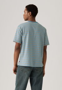 Striped t-shirt featuring blue, green, and tan horizontal stripes, short sleeves, and a round neckline. Material appears soft and lightweight.