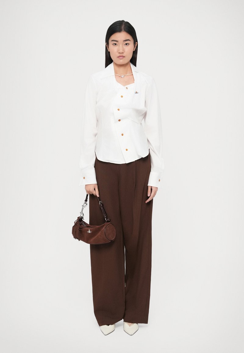White button-up shirt with orange buttons, brown wide-leg trousers, and a brown suede handbag, featuring silver hardware and tassels.