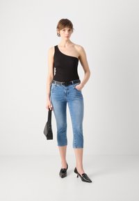 Bodysuit negro de un solo hombro, jeans cortos azul claro, cinturón negro, pequeña bolsa negra y tacones negros puntiagudos. Textura suave, ajuste casual.
