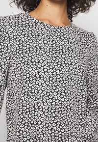 Tessuto a fantasia bianco e nero con motivo leopardato testurizzato e irregolare; scollo rotondo; materiale leggero; vestibilità leggermente ampia.