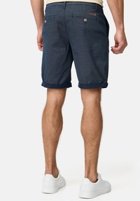 Pantalones cortos azul marino con un patrón de espiga, dobladillo rematado y dos bolsillos traseros. Fabricados con una tela texturizada de acabado suave.